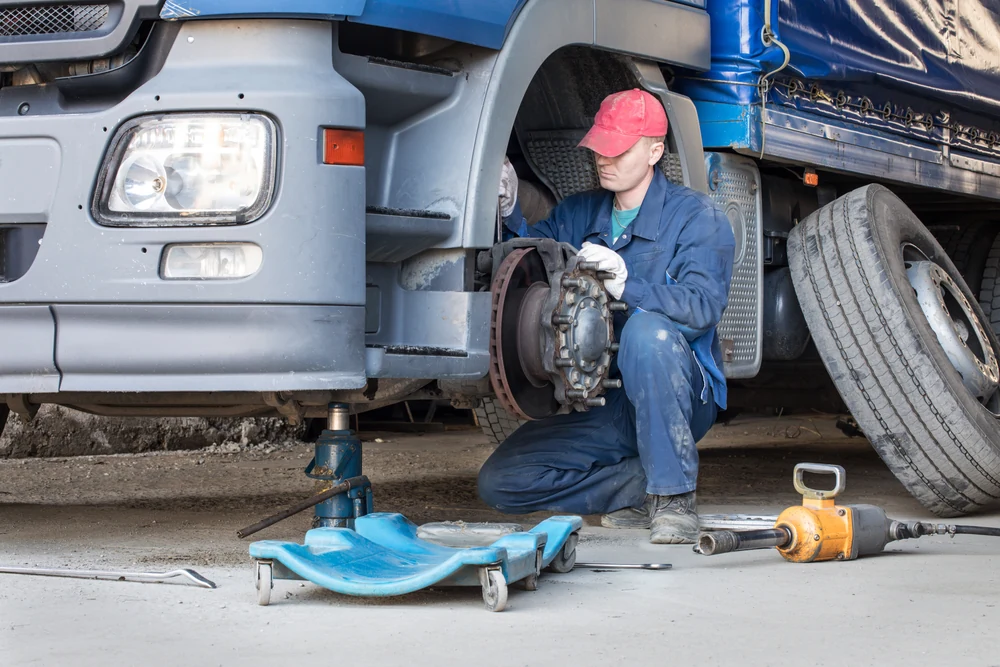 Man changing truck tyre and brakes